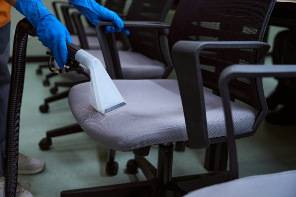Certified cleaning specialist using upholstery vacuum-cleaner for chairs